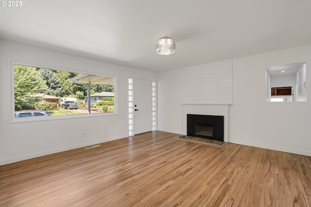 116 SE 153rd Ave, Portland, OR 97233 - unfurnished living room with light wood-type flooring, a brick fireplace, and baseboards