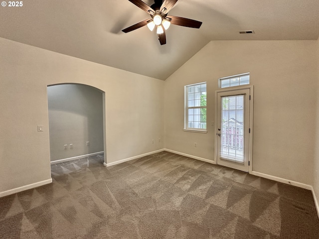 carpeted empty room featuring ceiling fan, visible vents, arched walkways, baseboards, and vaulted ceiling