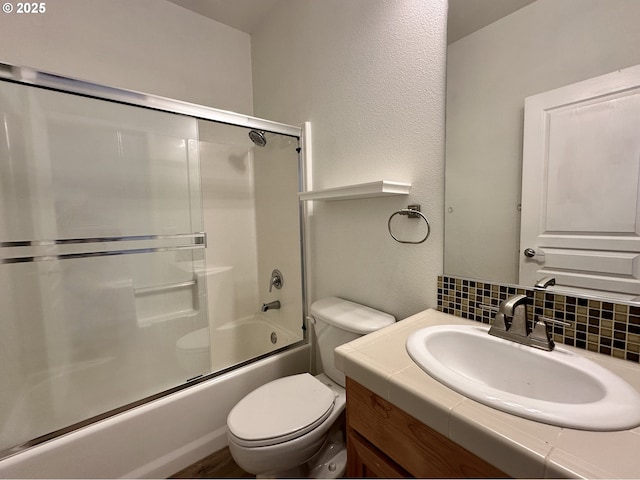 bathroom with backsplash, toilet, shower / bath combination with glass door, and vanity