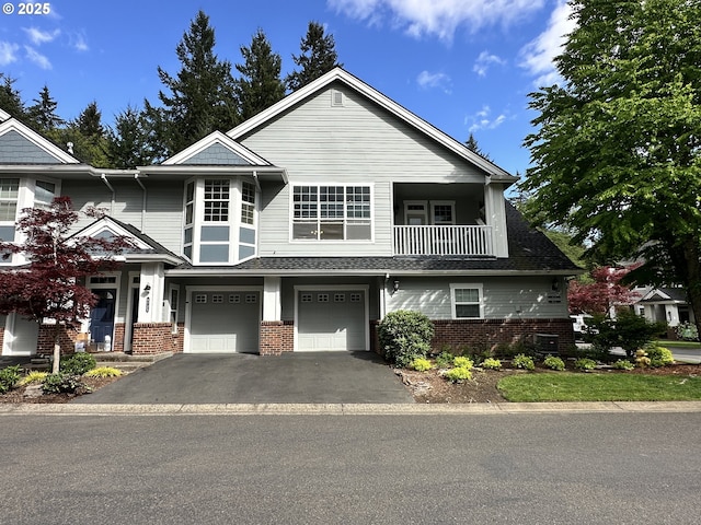 view of property with brick siding, driveway, a balcony, and a garage