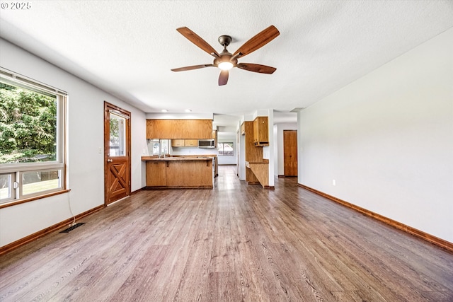 51945 SW Creekview Pl, Scappoose, OR 97056 - unfurnished living room with wood finished floors, ceiling fan, baseboards, and a textured ceiling