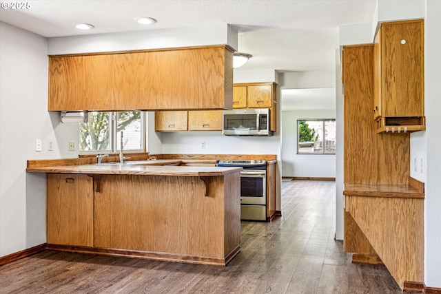 51945 SW Creekview Pl, Scappoose, OR 97056 - kitchen featuring stainless steel appliances, a peninsula, a breakfast bar area, dark wood finished floors, and recessed lighting