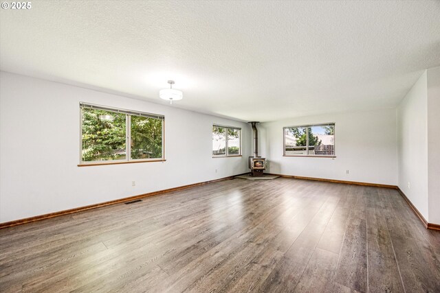 51945 SW Creekview Pl, Scappoose, OR 97056 - spare room featuring wood finished floors, a textured ceiling, baseboards, and a wood stove