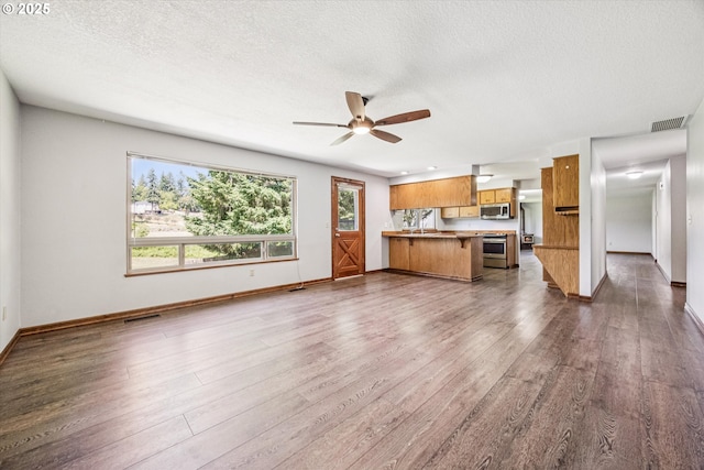 51945 SW Creekview Pl, Scappoose, OR 97056 - unfurnished living room featuring dark wood-style floors, baseboards, a ceiling fan, and a textured ceiling