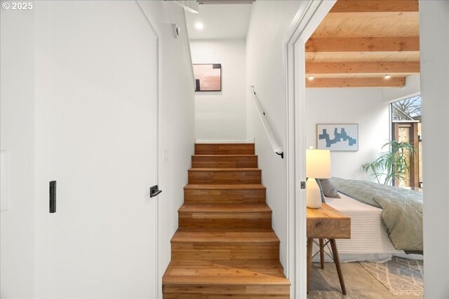 stairway with beam ceiling and wood finished floors