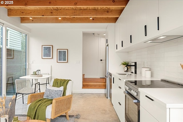 kitchen featuring decorative backsplash, stainless steel range with electric stovetop, beam ceiling, white cabinets, and a sink