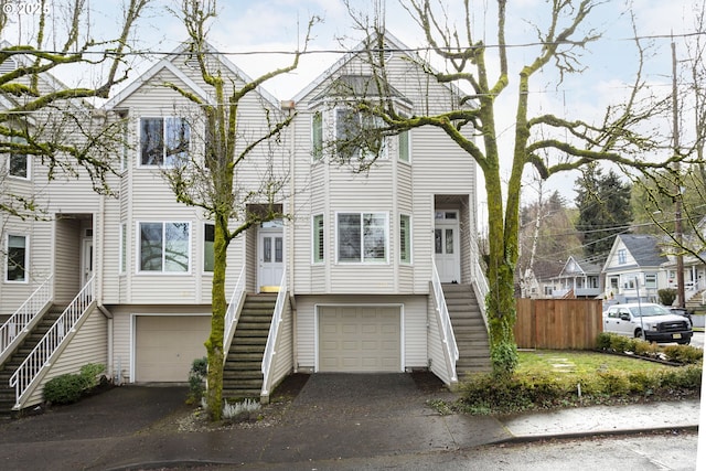 view of front of house featuring stairs, driveway, fence, and a garage