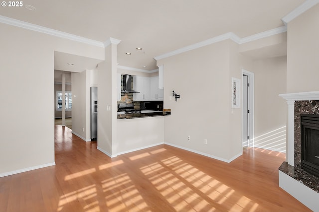 unfurnished living room with light wood-style floors, a fireplace, baseboards, and crown molding