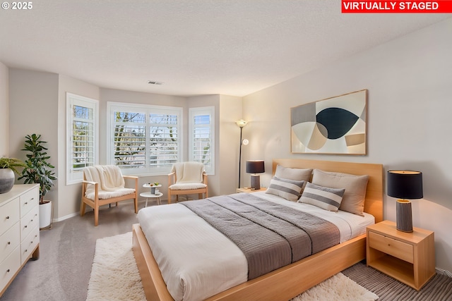 bedroom with a textured ceiling, carpet floors, visible vents, and baseboards