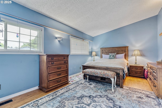 bedroom featuring a textured ceiling, wood finished floors, and baseboards