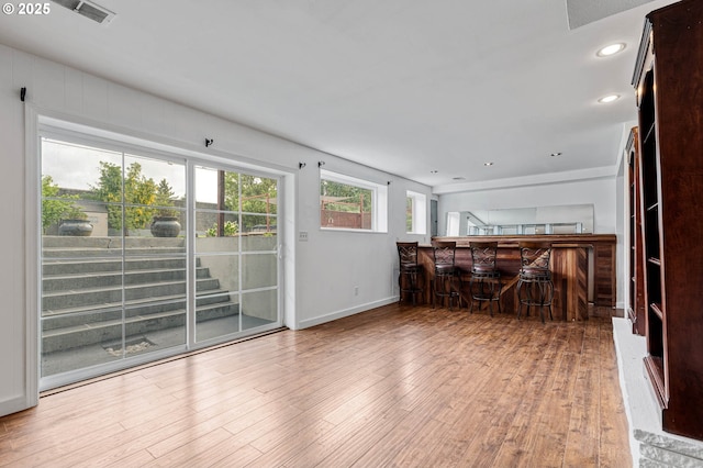 living room with a bar, wood finished floors, baseboards, and recessed lighting