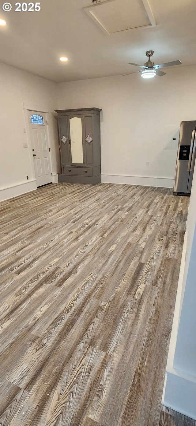 unfurnished living room featuring wood finished floors, baseboards, attic access, and recessed lighting