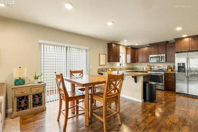 21889 SW Cedar Brook Way, Sherwood, OR 97140 - kitchen featuring stainless steel appliances, dark wood-style floors, recessed lighting, a breakfast bar, and dark brown cabinetry