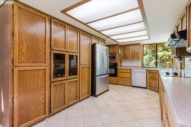 16649 S Holcomb Blvd, Oregon City, OR 97045 - kitchen with black appliances, under cabinet range hood, brown cabinets, light countertops, and light tile patterned flooring