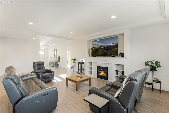living area featuring light wood finished floors, baseboards, a glass covered fireplace, and recessed lighting