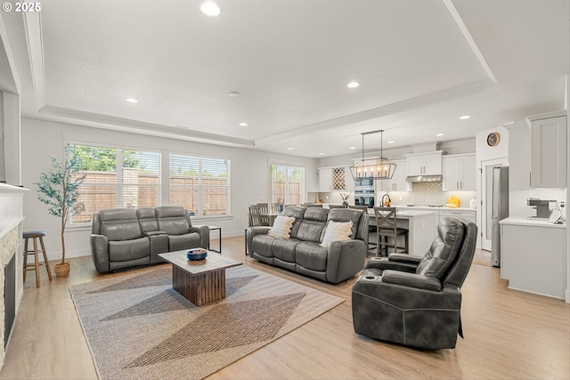7705 NE 181st Ct, Vancouver, WA 98682 - living area featuring a tray ceiling, light wood-style flooring, a glass covered fireplace, and recessed lighting