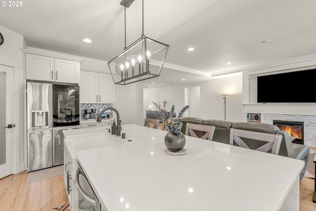 7705 NE 181st Ct, Vancouver, WA 98682 - kitchen with stainless steel appliances, a large island with sink, light wood finished floors, a fireplace, and a chandelier