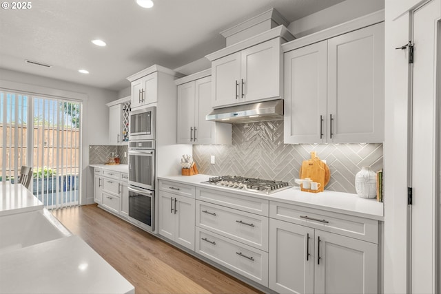 7705 NE 181st Ct, Vancouver, WA 98682 - kitchen featuring under cabinet range hood, stainless steel appliances, light countertops, recessed lighting, and light wood-style floors