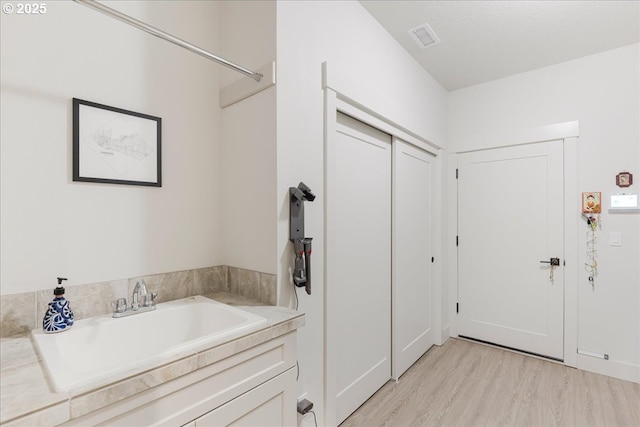 bathroom with wood finished floors, a sink, and visible vents
