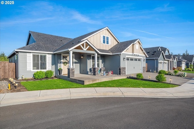 view of front of property featuring covered porch, fence, an attached garage, board and batten siding, and a front yard