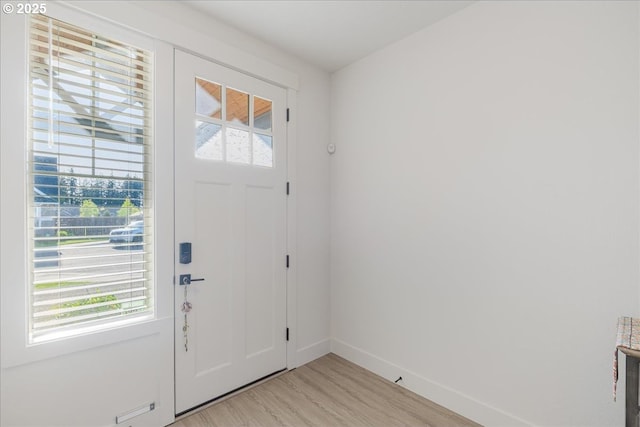 entrance foyer with baseboards, a healthy amount of sunlight, and light wood-type flooring