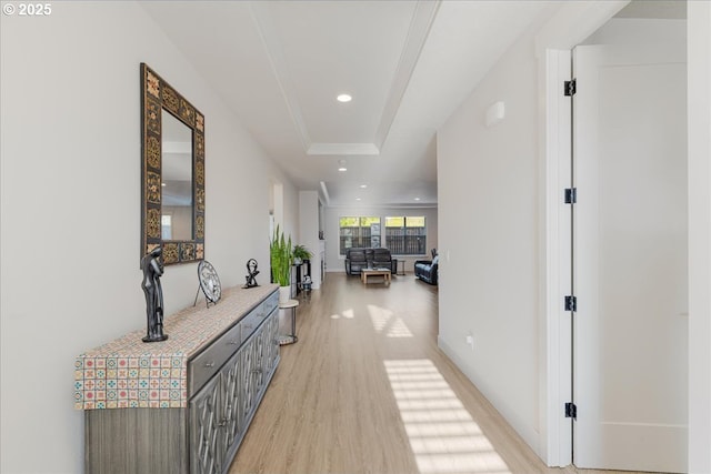 hall with a raised ceiling, baseboards, recessed lighting, and light wood-style flooring