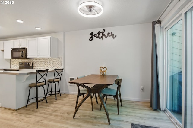 dining room featuring healthy amount of natural light, light wood-style flooring, recessed lighting, and baseboards