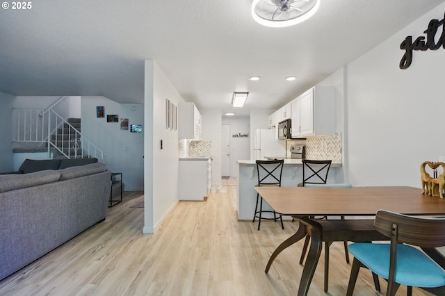 dining space featuring light wood-type flooring, stairs, recessed lighting, and baseboards