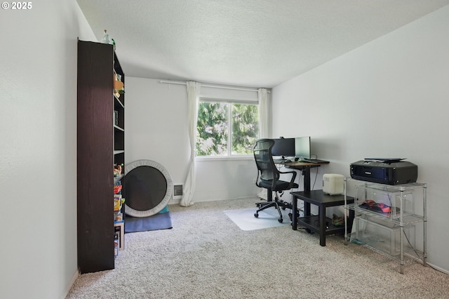 carpeted home office featuring a textured ceiling