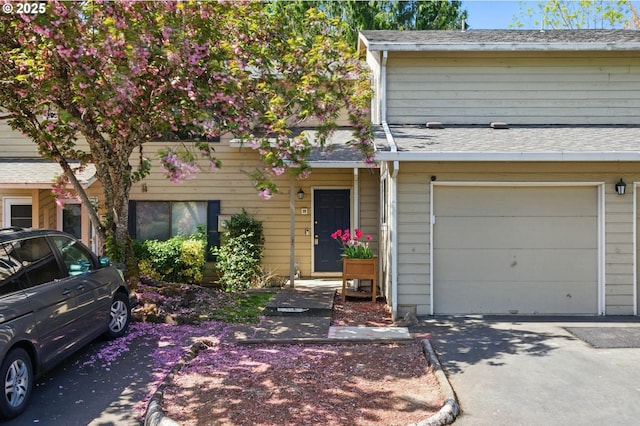 multi unit property featuring a garage, roof with shingles, and concrete driveway