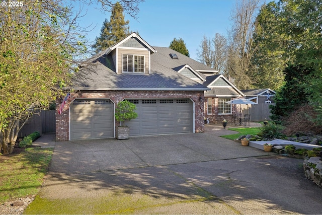 view of front of property featuring brick siding, roof with shingles, concrete driveway, fence, and a garage