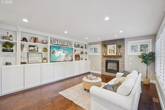 living area with dark wood-type flooring, a fireplace, a wealth of natural light, and recessed lighting