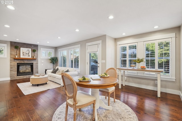 dining space with a large fireplace, recessed lighting, dark wood finished floors, and baseboards