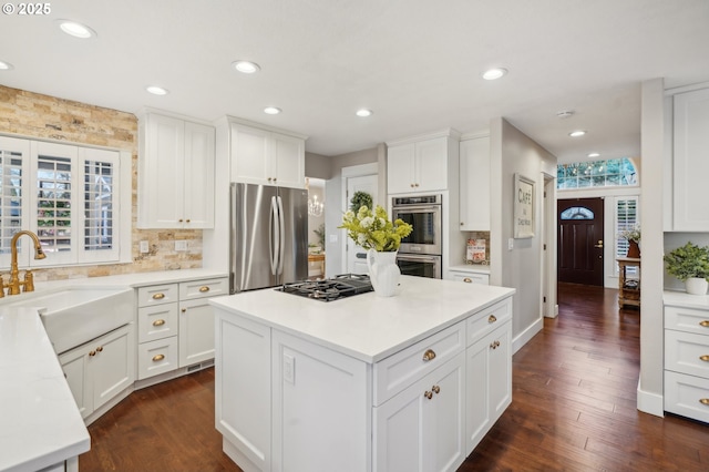 kitchen with appliances with stainless steel finishes, dark wood finished floors, a healthy amount of sunlight, and a sink