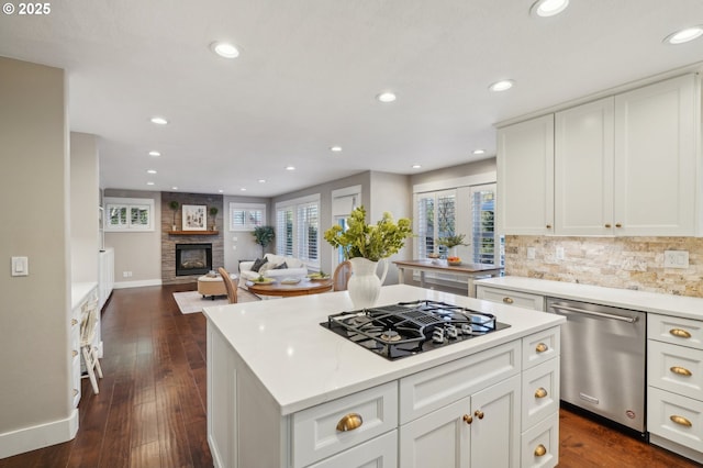 kitchen with black gas stovetop, a large fireplace, backsplash, dishwasher, and dark wood finished floors