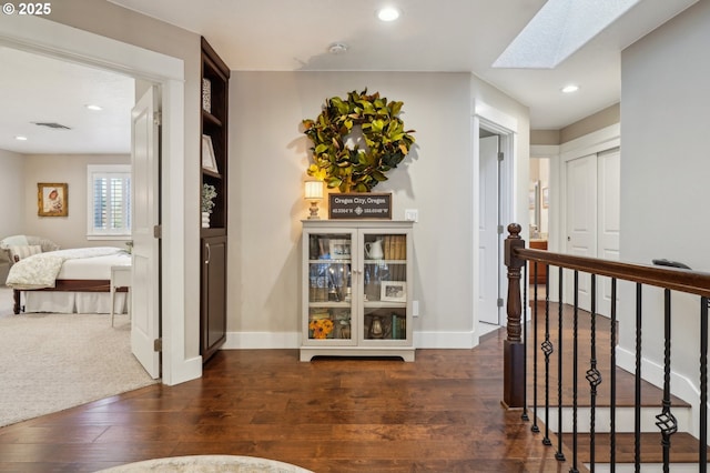 hallway with baseboards, dark wood-style flooring, a skylight, and recessed lighting