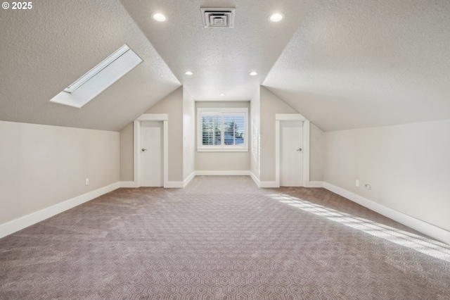 additional living space featuring lofted ceiling with skylight, carpet flooring, and baseboards