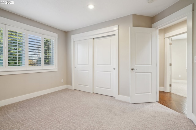 unfurnished bedroom with recessed lighting, a closet, light colored carpet, and baseboards