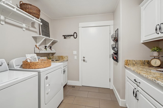 washroom with light tile patterned floors, cabinet space, visible vents, independent washer and dryer, and a sink