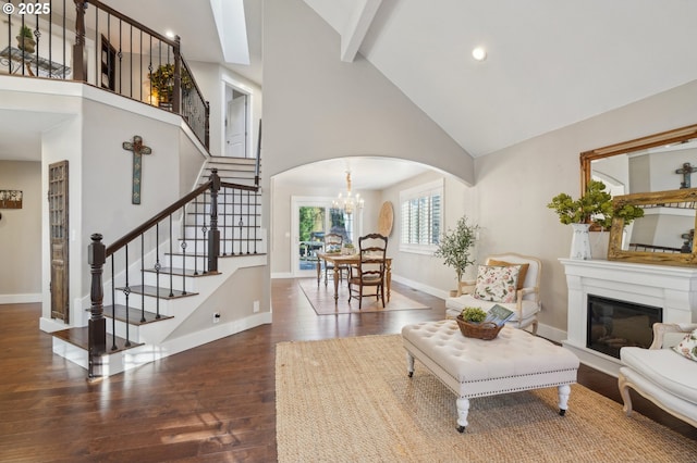 living area with high vaulted ceiling, arched walkways, baseboards, and wood finished floors