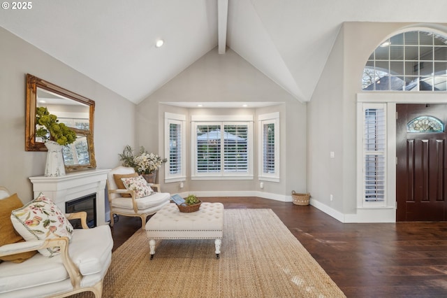 entryway with high vaulted ceiling, wood finished floors, baseboards, beam ceiling, and a glass covered fireplace