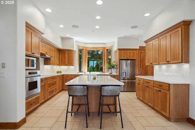 20754 SW Prindle Rd, Tualatin, OR 97062 - kitchen with appliances with stainless steel finishes, a sink, tasteful backsplash, a kitchen bar, and light countertops