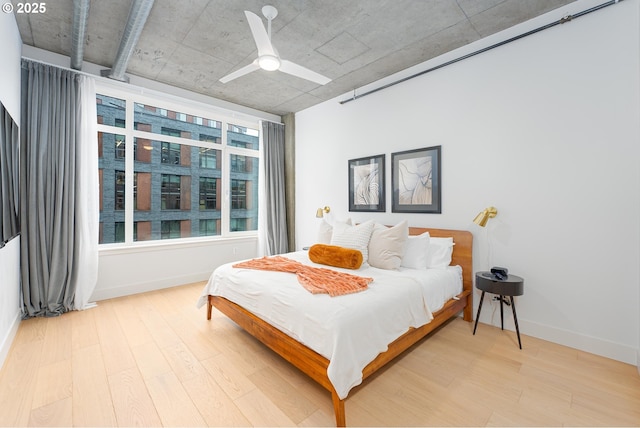 bedroom with ceiling fan, light wood finished floors, and baseboards