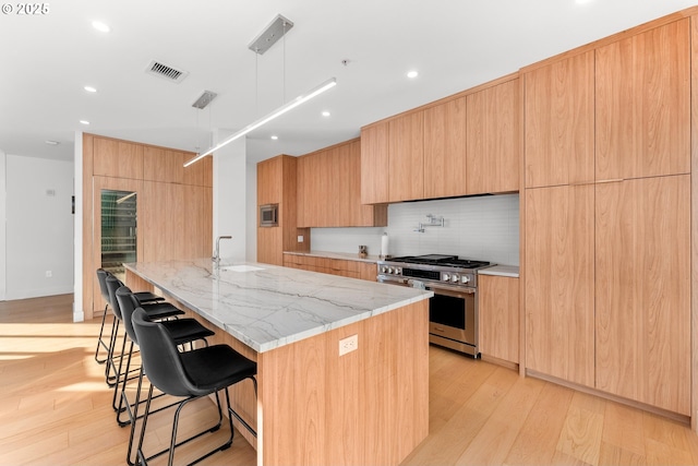 kitchen featuring a spacious island, modern cabinets, light stone counters, stainless steel appliances, and pendant lighting