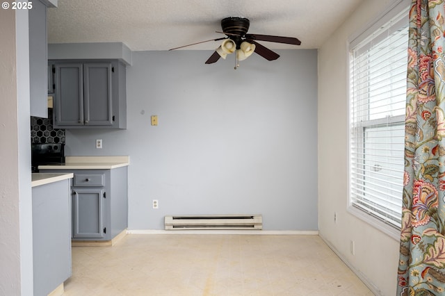 kitchen featuring gray cabinets, stove, ceiling fan, baseboard heating, and a textured ceiling