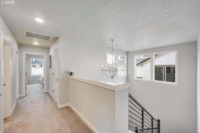2511 S White Salmon Dr, Ridgefield, WA 98642 - corridor with an upstairs landing, a chandelier, a textured ceiling, light colored carpet, and plenty of natural light