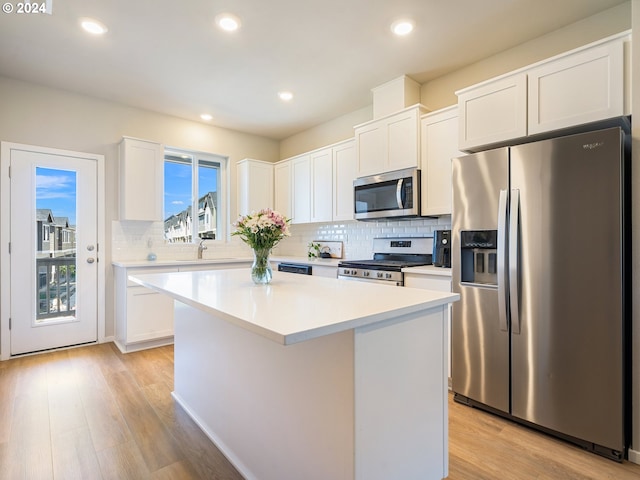 kitchen featuring stainless steel appliances, light wood-type flooring, white cabinetry, and a center island