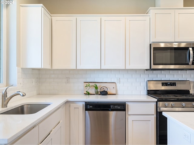 kitchen featuring white cabinetry, appliances with stainless steel finishes, backsplash, and a sink