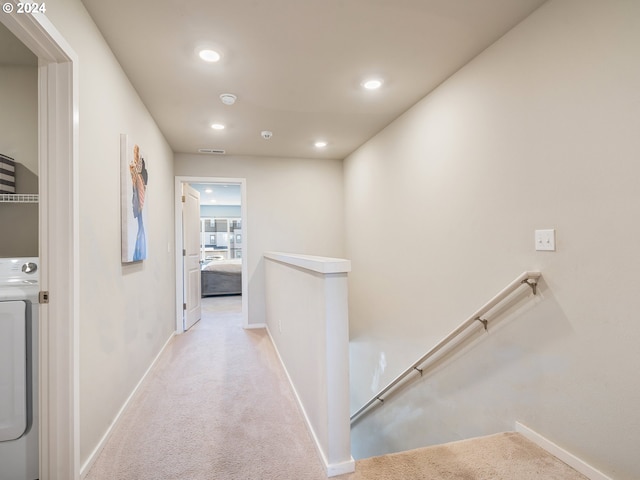 hall featuring carpet, baseboards, and an upstairs landing