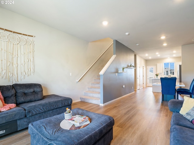 living area featuring light wood-type flooring, baseboards, recessed lighting, and stairs